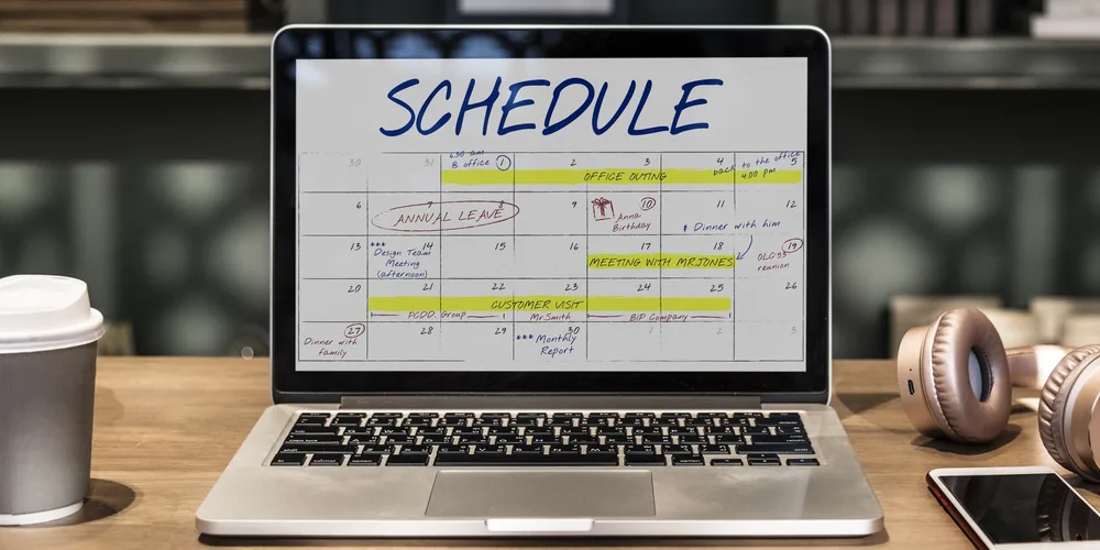Laptop showing a schedule on a coworking desk, representing WordPress booking plugin iCal sync