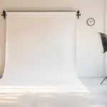 Empty daylight photography studio with a seamless backdrop, softbox lights and a wall clock, a space rented by the hour